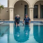 lucid-origin_Two_pool_maintenance_technicians_in_branded_uniforms_inspecting_a_large_villa_po-0